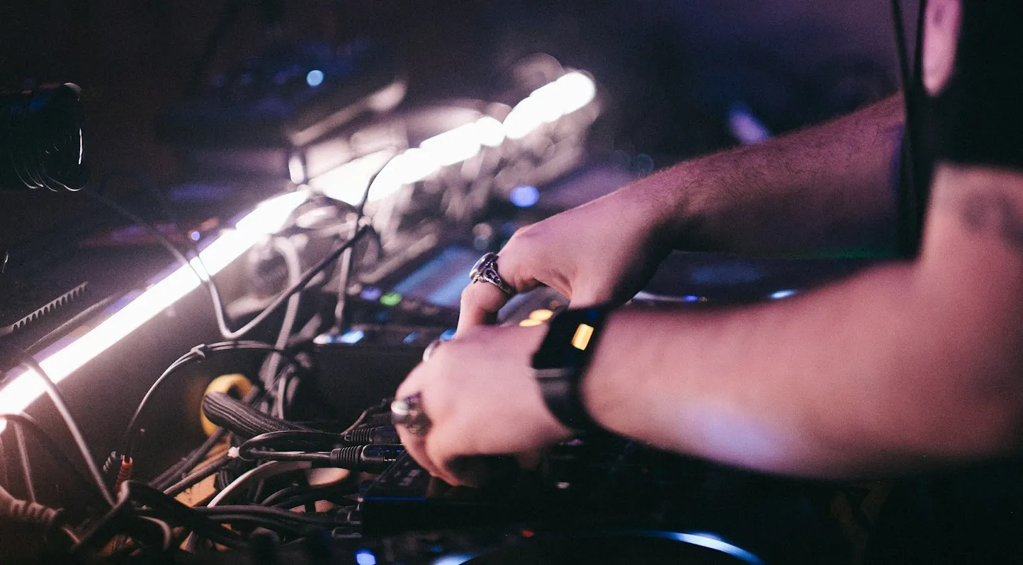 Mains du DJ sur la table de mixage, dans la lumière